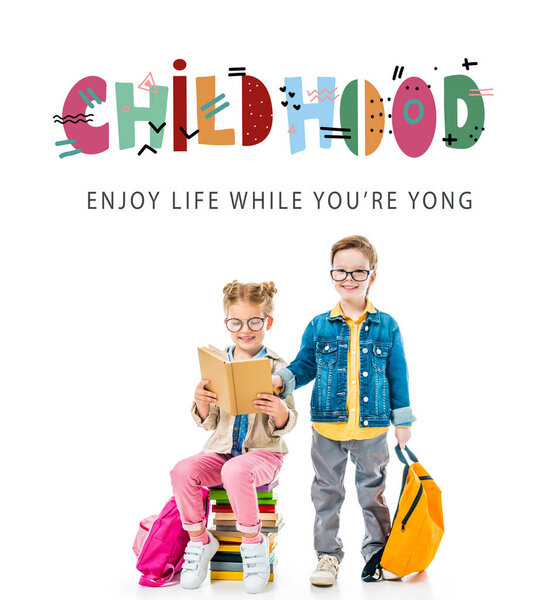 schoolchildren in eyeglasses studying and sitting on books with backpacks, isolated on white with "childhood - enjoy life while you are young" lettering