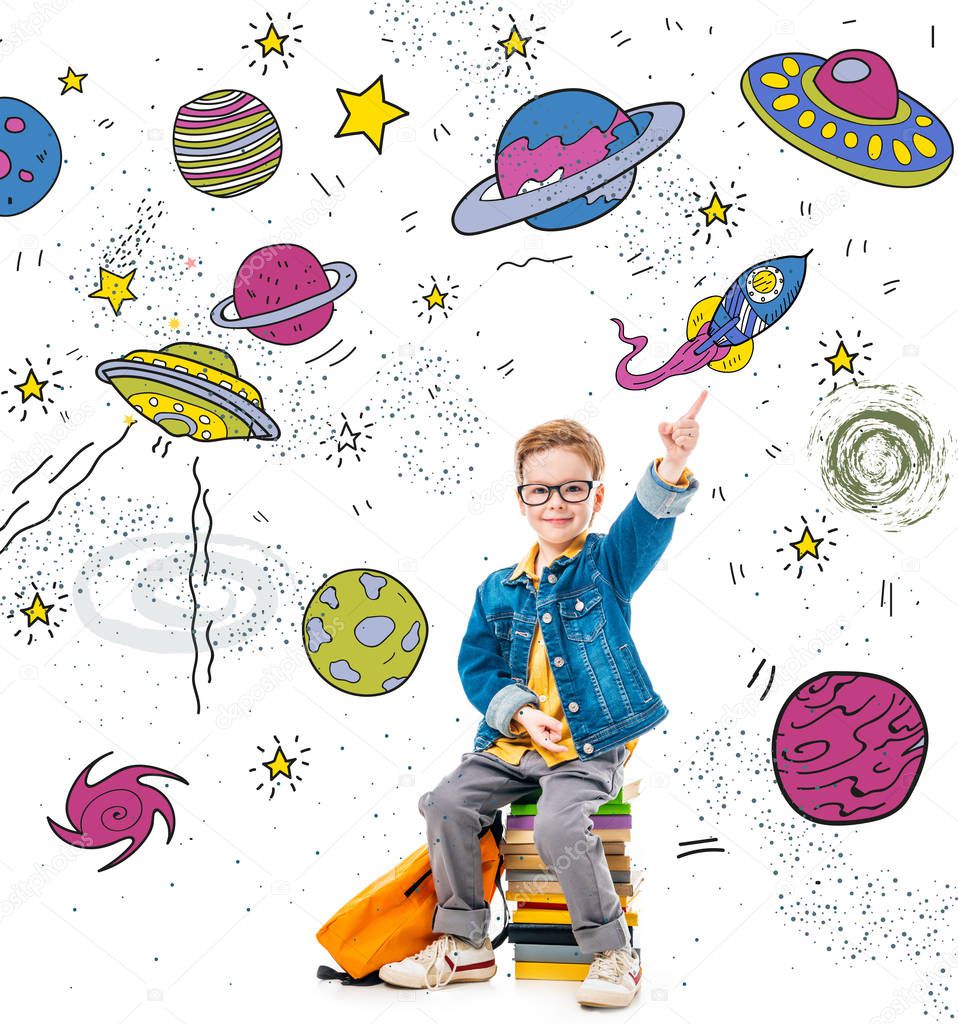 smiling schoolboy pointing up while sitting on pile of books with backpack, isolated on white with fantasy universe, planets and spaceships