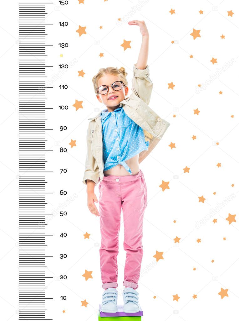 happy kid in eyeglasses standing on pile of books to be higher isolated on white with stars and growth measures