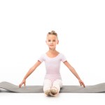 Child practicing gymnastics exercises on fitness mat isolated on white background