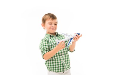 Beyaz arka plan üzerinde izole oyuncak uçak ile oynarken küçük boy gülümseyerek