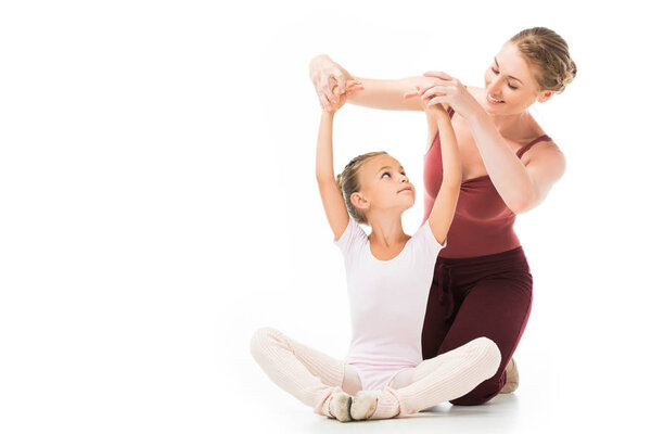 smiling female trainer helping little kid exercising isolated on white background 