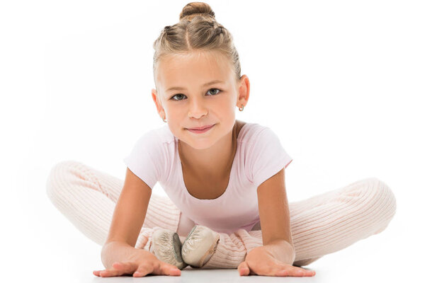 adorable little ballerina stretching and looking at camera isolated on white background 