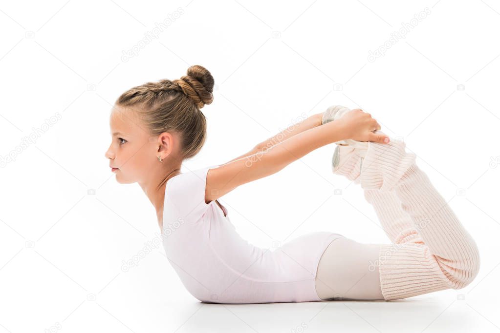 side view of focused little ballerina stretching isolated on white background 