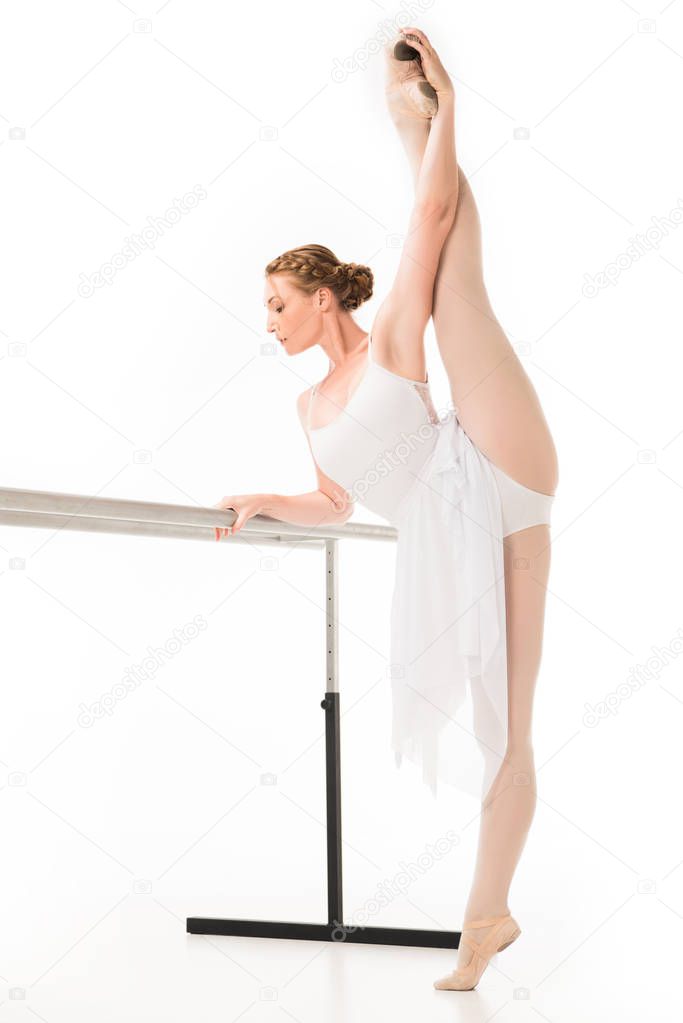 adult ballerina in tutu and pointe shoes stretching at ballet barre stand isolated on white background 