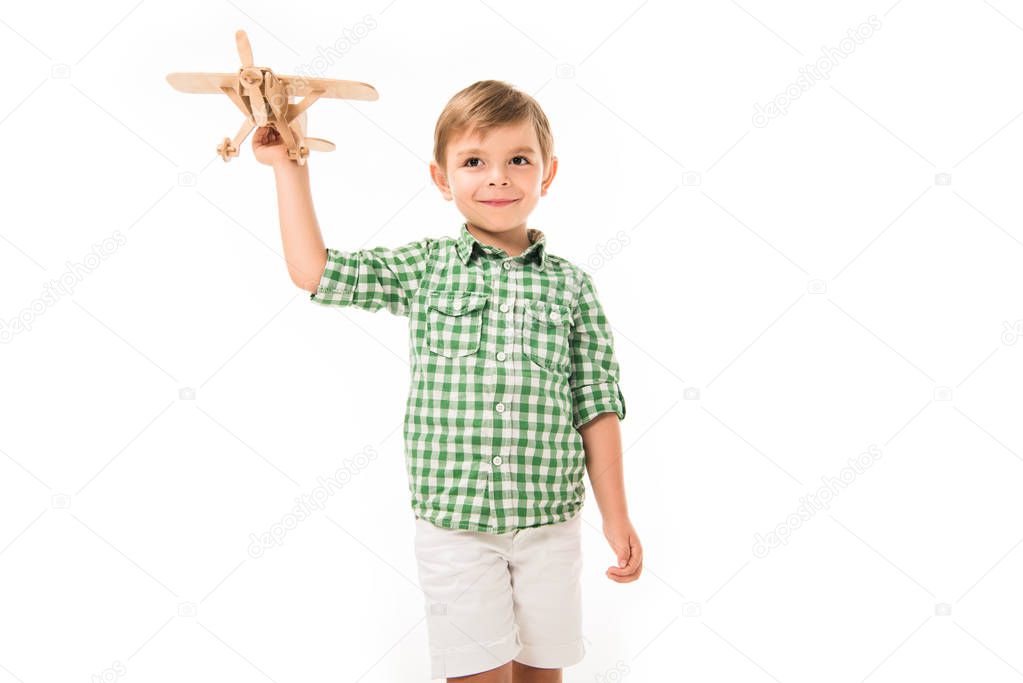 happy little boy playing with wooden toy plane isolated on white background