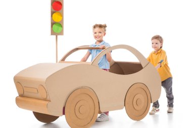 Onu, beyaz ve arka plan üzerinde trafik ışıkları iterek kardeşi ise karton arabayı kız kardeşi