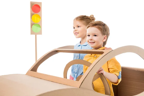 happy siblings playing with cardboard car and traffic lights, isolated on white