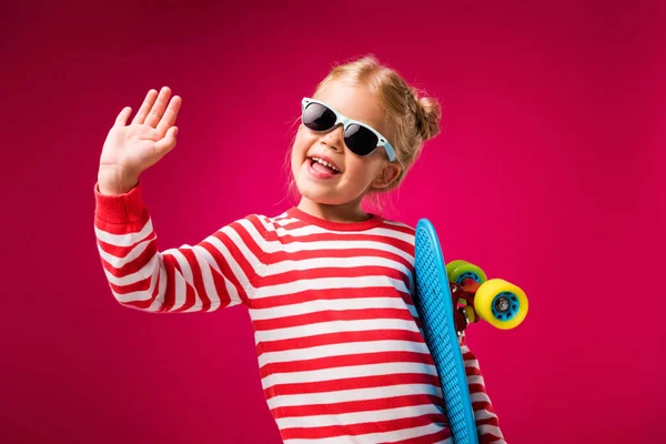 Excited Stylish Kid Sunglasses Holding Penny Board Waving Isolated Red — Stock Photo, Image
