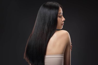 back view of beautiful asian woman with straight and shiny hair isolated on black clipart