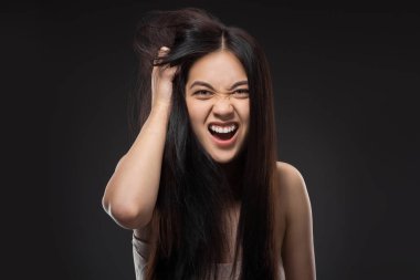 portrait of emotional asian woman with dark healthy hair isolated on black clipart