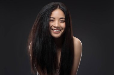 portrait of happy asian woman with beautiful and healthy dark hair looking at camera isolated on black clipart