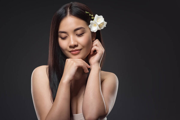 portrait of beautiful young asian woman with white flowers in hair isolated on black