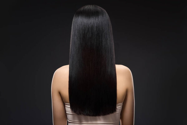 back view of woman with beautiful shiny hair isolated on black