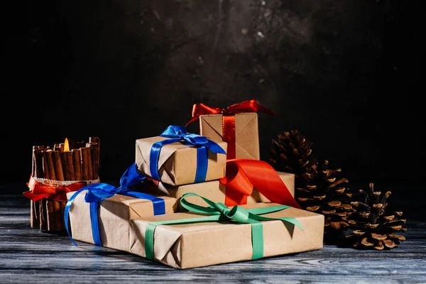 Vista Ravvicinata Regali Natale Avvolti Candele Pigne Sul Tavolo Legno — Foto stock gratuita