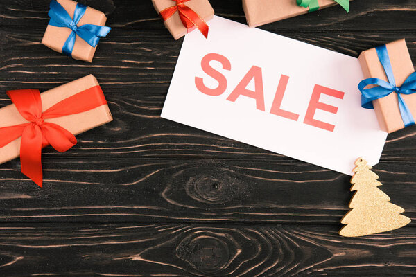 верхний вид на знак продажи и рождественские подарки на деревянной поверхности
