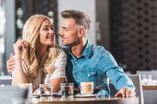 happy romantic couple hugging at table in restaurant