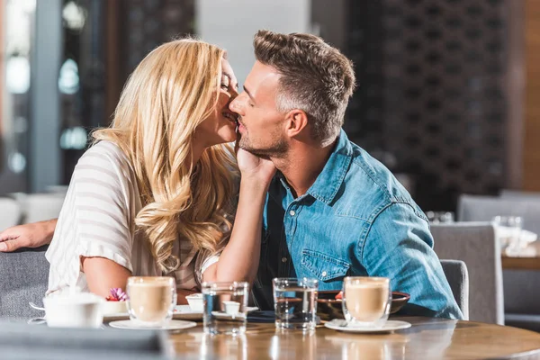 stock image affectionate couple kissing at table in cafe