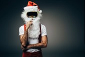 Weihnachtsmann in Skimaske steht isoliert auf grauem Hintergrund 