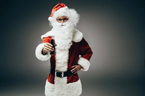 笑顔サンタ クロース コスチューム立っている灰色の背景に分離したクリーム ソーダの瓶で  — 無料ストックフォト
