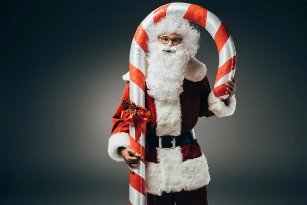 Uśmiechający Się Santa Claus Kostium Stojąc Duże Pasiasty Boże Narodzenie — Darmowe zdjęcie stockowe