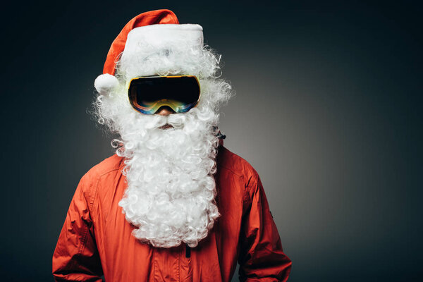 portrait of santa claus in ski mask and windbreaker standing isolated on grey background 