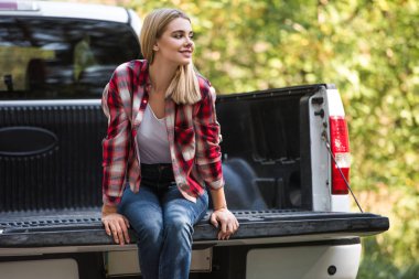 beautiful happy woman sitting in trunk of pick up car outdoors  clipart