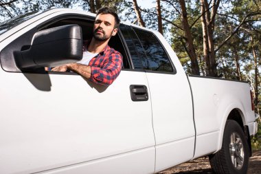 araba ve orman kanat aynaya bakarak otururken ciddi yakışıklı delikanlı al 