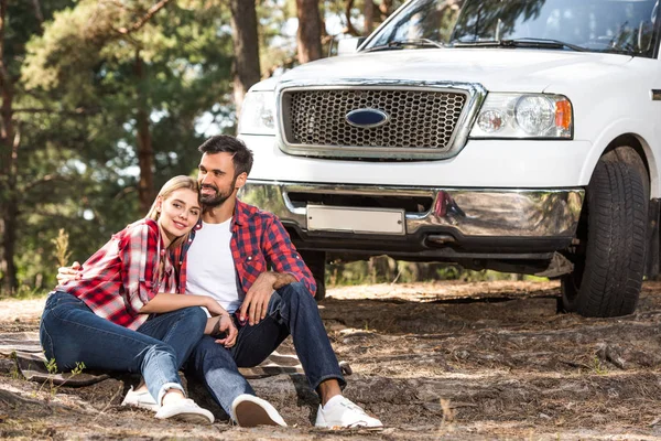 Smiling Young Sitting Ground Pick Car Forest — Stock Photo, Image
