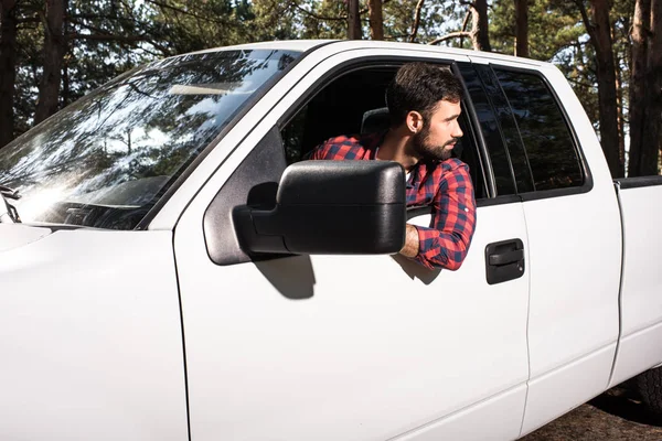 自信的年轻英俊的男子坐在拿起车 看着远离森林 — 图库照片