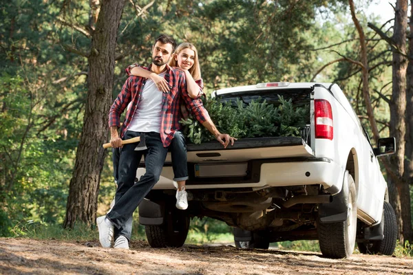 Young Man Holding Axe Standing Girlfriend Sitting Car Trunk Christmas — Stock Photo, Image