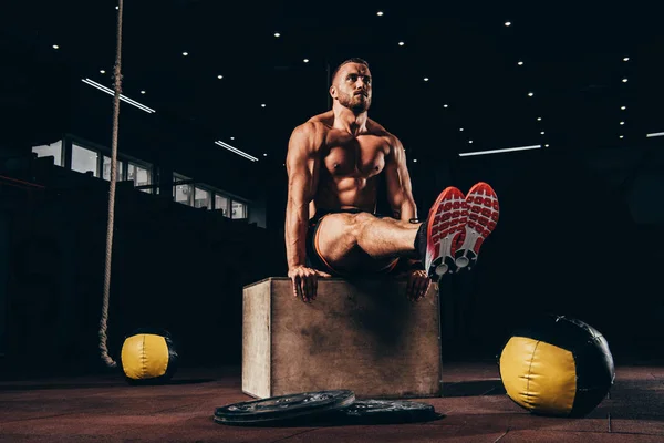 英俊的运动男子在黑暗的健身房在立方体上执行武器平衡 — 图库照片