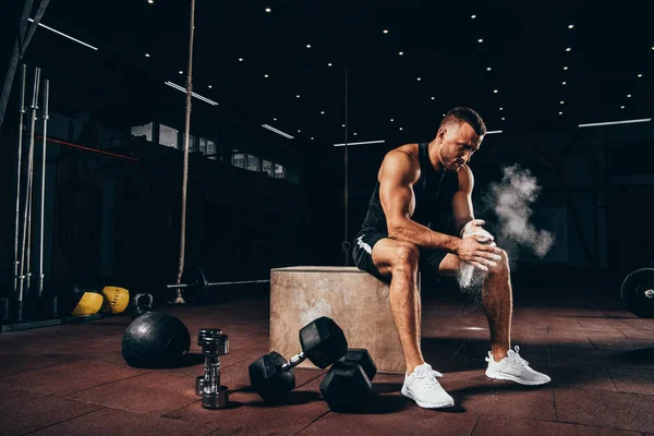 Knappe Atletische Man Zit Kubus Met Fitnessapparatuur Rond Ongeëvenaarde Handen — Stockfoto