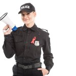 Mujer policía sonriente con SIDA cinta roja conciencia y megáfono aislado en blanco