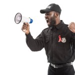 Angry Afryki amerykański oficer policji z aids świadomości czerwoną wstążką krzycząc z megafon na białym tle