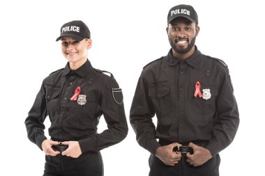 confident multiethnic police officers with aids awareness red ribbons looking at camera isolated on white clipart