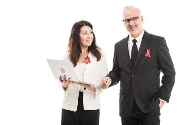 smiling multiethnic adult businesspeople with aids awareness red ribbons working together with laptop isolated on white clipart