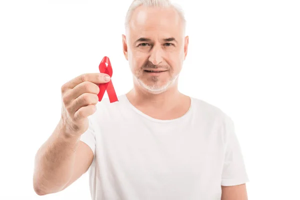 快乐成熟的人在空白白色 T恤持有艾滋病意识红色丝带和看着在白色查出的相机 — 图库照片