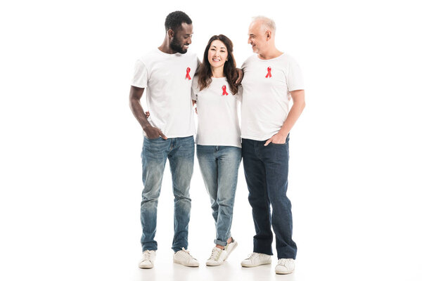 multiethnic group of people in blank white t-shirts with aids awareness red ribbons embracing and looking at each other isolated on white