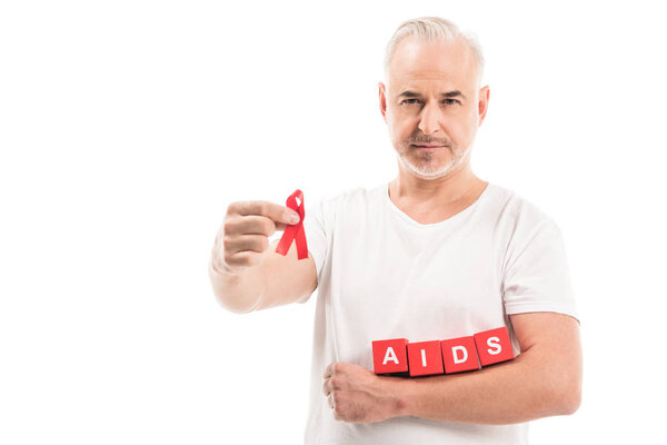 mature man in blank white t-shirt with aids awareness red ribbon and blocks with AIDS lettering isolated on white