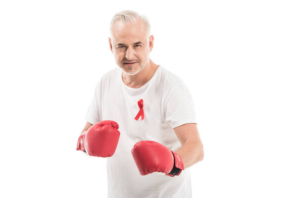 serious mature man in blank white t-shirt with aids awareness red ribbon and boxing gloves isolated on white, fighting aids concept