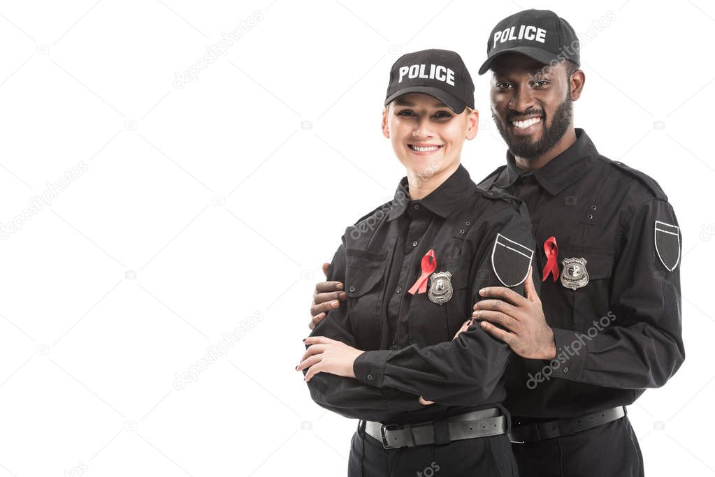 smiling police officers with aids awareness red ribbons looking at camera isolated on white