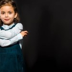 Portrait of cute schoolchild looking at camera isolated on black