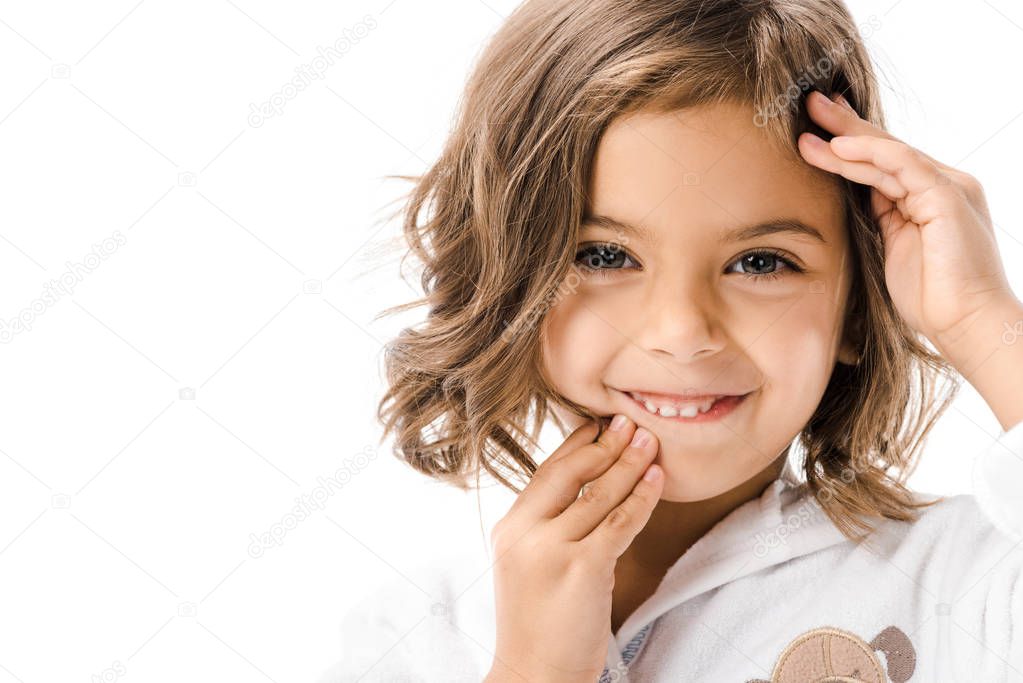 portrait of smiling child touching face and looking at camera isolated on white