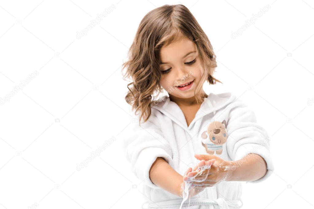 portrait of little kid in bathrobe washing hands with soap isolated on white