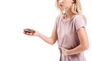 cropped image of woman showing stomach pain and holding chocolate doughnut isolated on white clipart