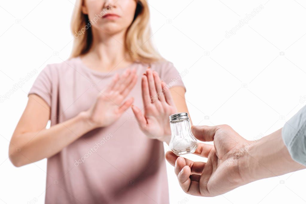 cropped image of woman rejecting saltcellar with powdered salt isolated on white