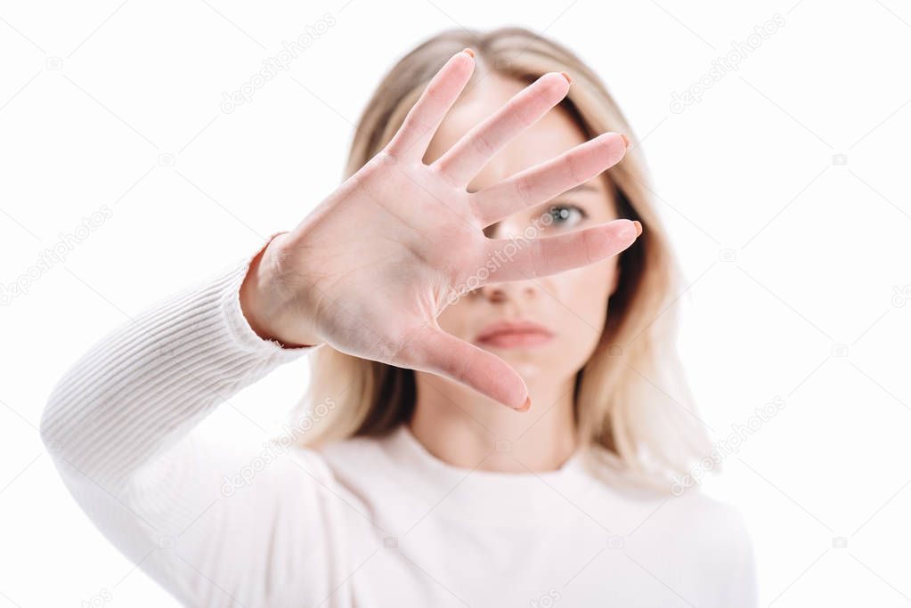 blonde woman showing stop sign and looking at camera isolated on white