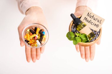 cropped image of woman holding bowls with natural medicine oil and pharmacological pills isolated on white clipart