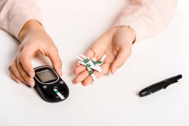 cropped image of woman holding glucometer and strips isolated on white, diabetes concept clipart